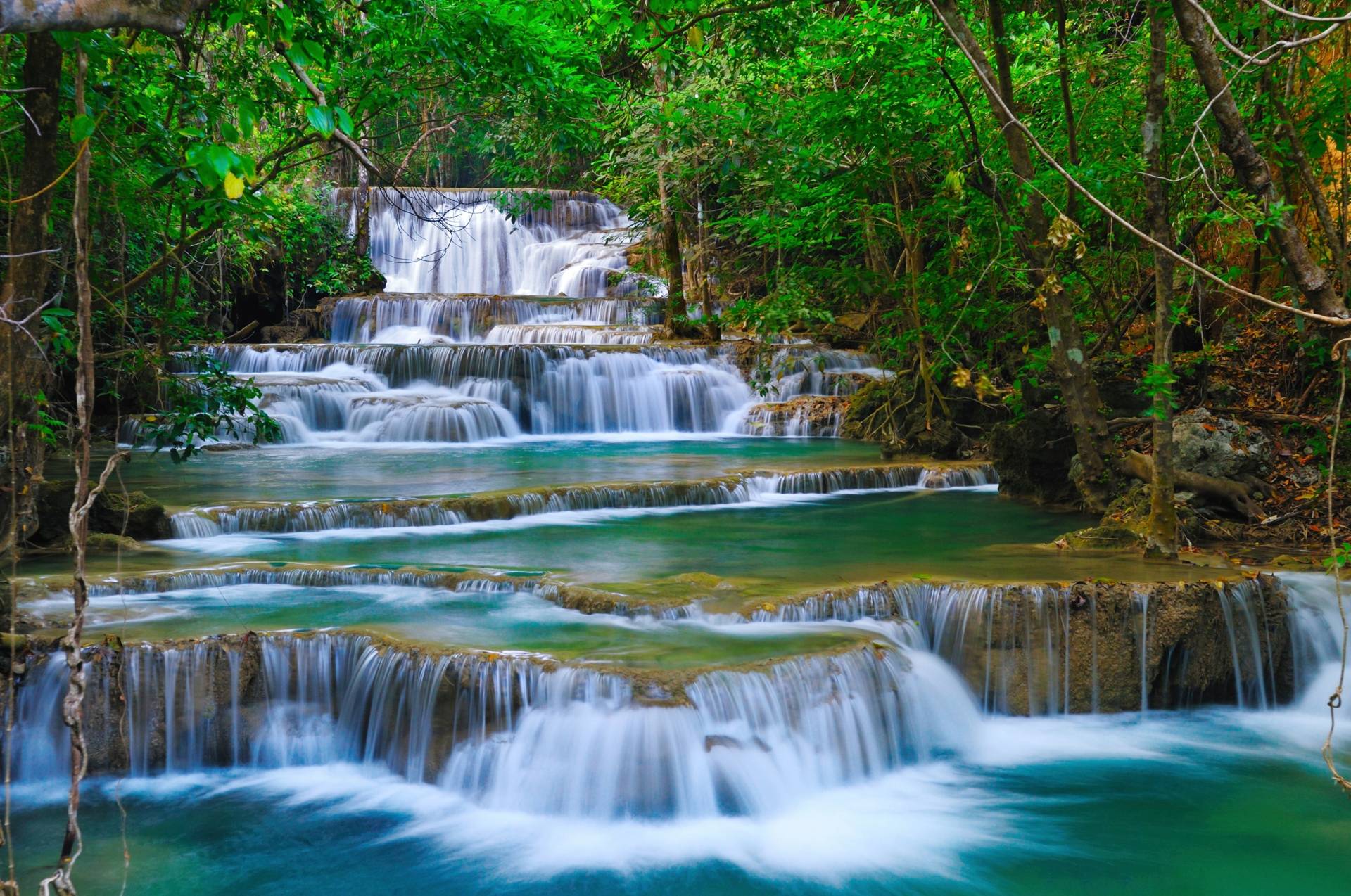 Papermoon Fototapete »WASSERFALL-BÄUME FLUSS SEE STEINE BLUMEN BERGE SONNE« von Papermoon